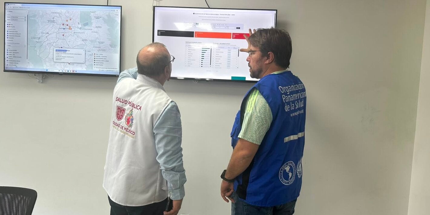 PAHO and MoH staff in front of a screen showing a dashboard