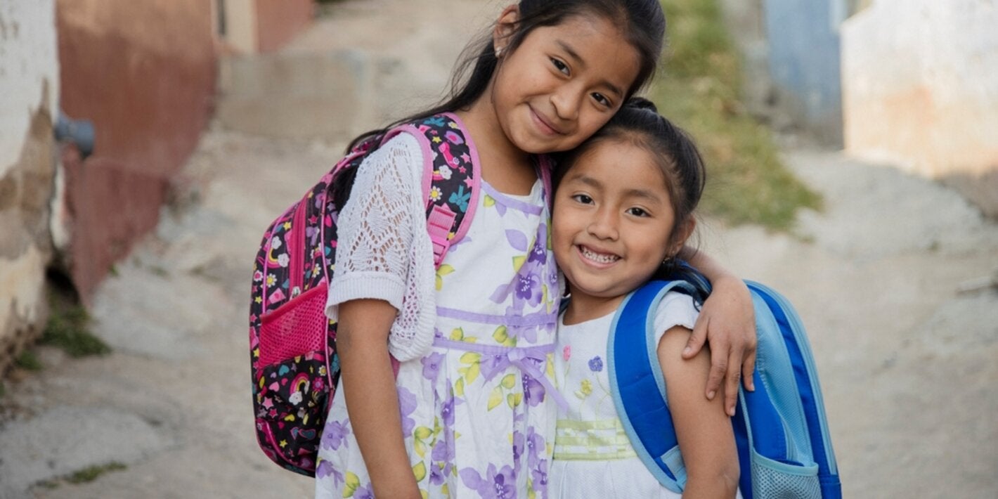 Dos chicas abrazadas con sus mochilas
