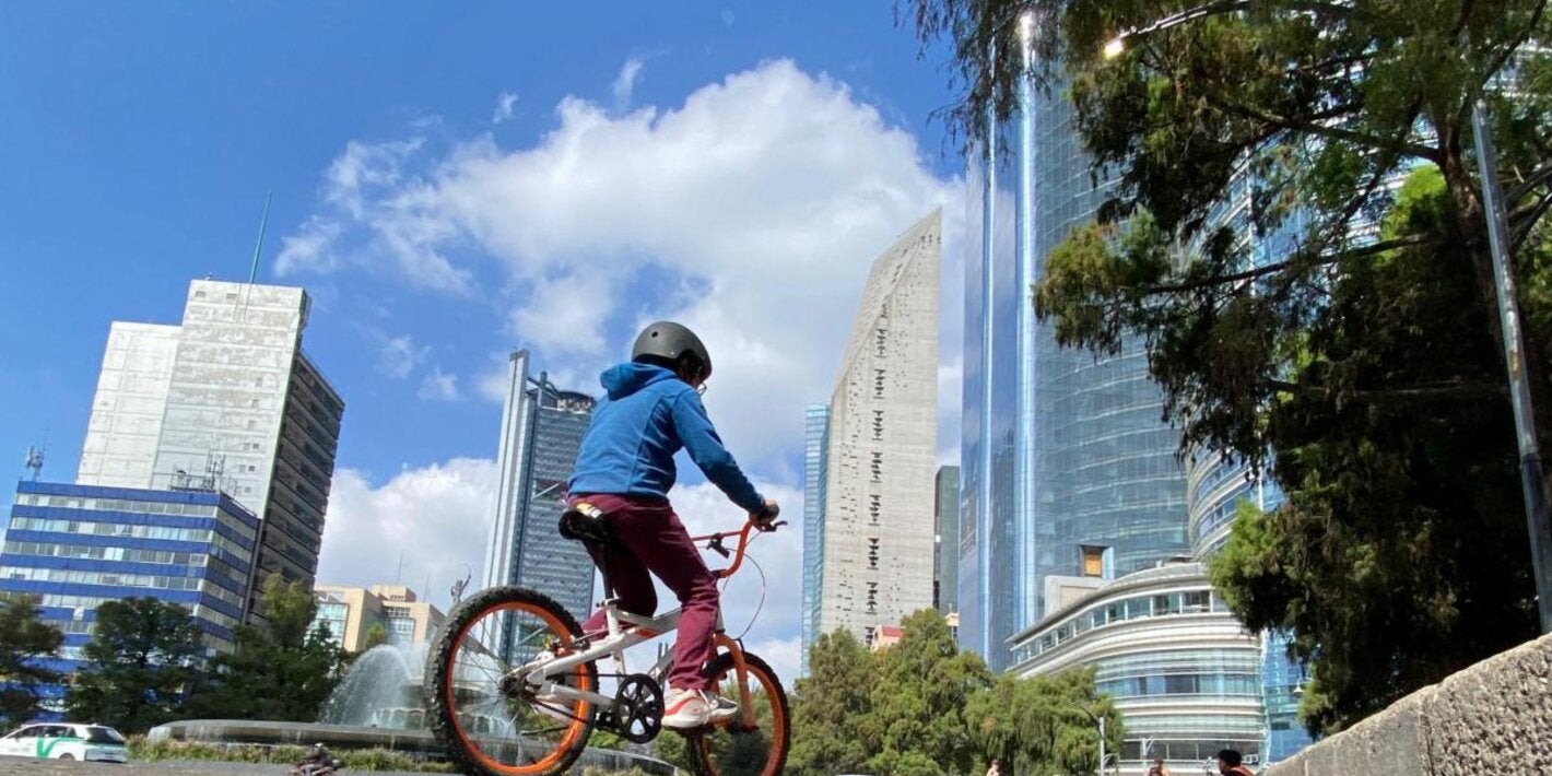 Niño en bicicleta en Ciudad de México con un cielo azul