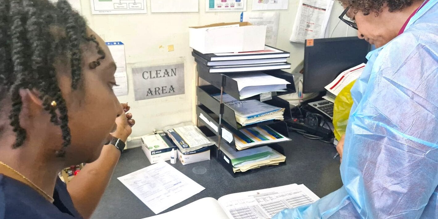 (L-R) A member of the POSGH team review records with Ms Valerie Wilson, Laboratory Expert, Caribbean MedLab Foundation