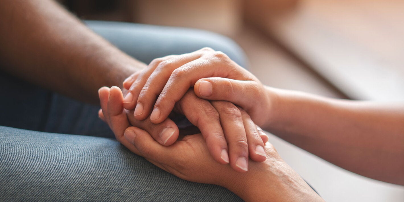 One person is offering support to another by holding his hands
