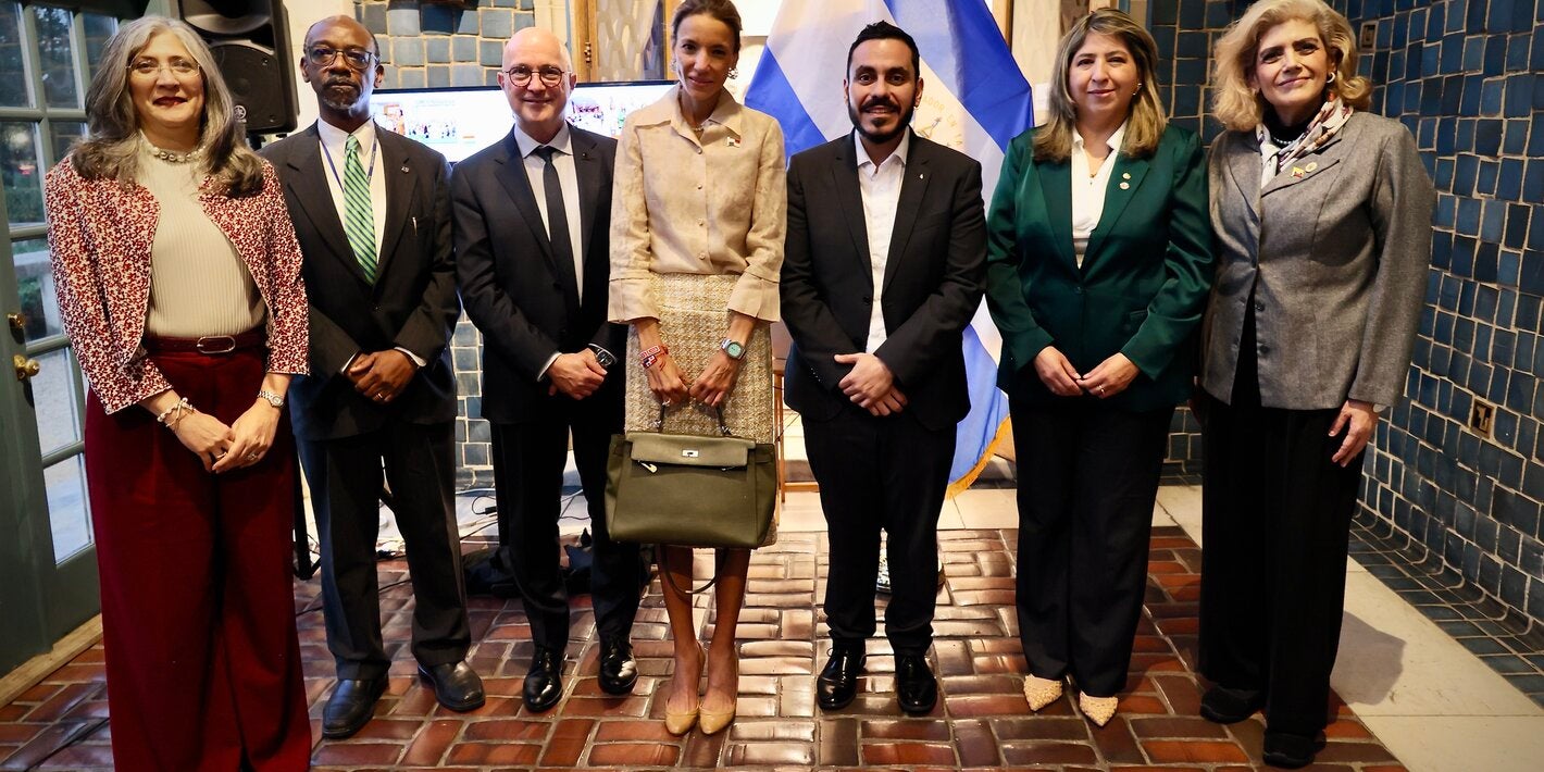siete personas paradas en frente de la bandera de El Salvador