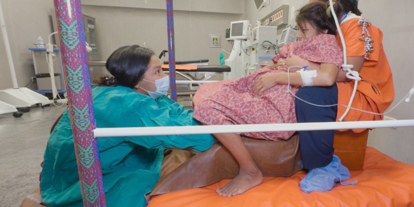 Woman in labor assisted by two health professionals at the Intercultural Hospital of Atalaya, in Ucayali, Peru.