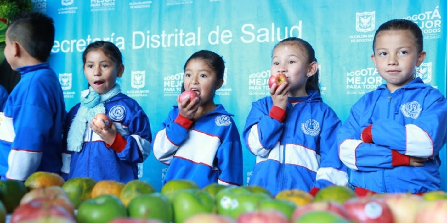 Niños y niñas vestidos con uniforme escolar deportivo, comiendo unas manzanas
