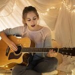 Mujer mirando el atardecer por la ventana, con una mascarilla cubriendo su cara