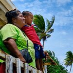 A woman and a boy looking out from a wood house