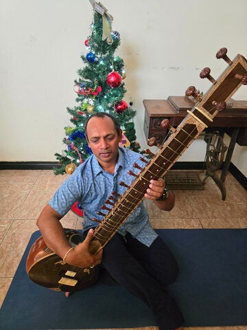 Dr. Nagassar playing the sitar his grandmother gifted him.