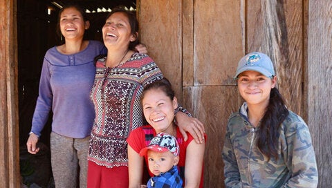 Cuatro mujeres sonríen en la puerta de una cabaña