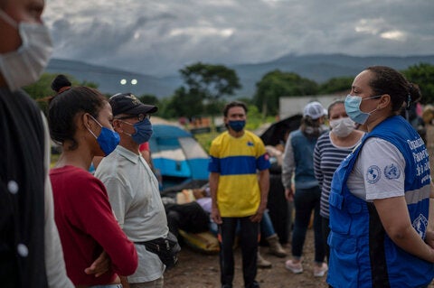 Training in the field. Woman wearing PAHO vest speaks to others outdoors