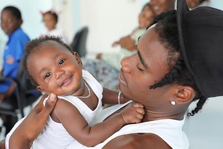 Infant smiling at camera while in the arms of her young father