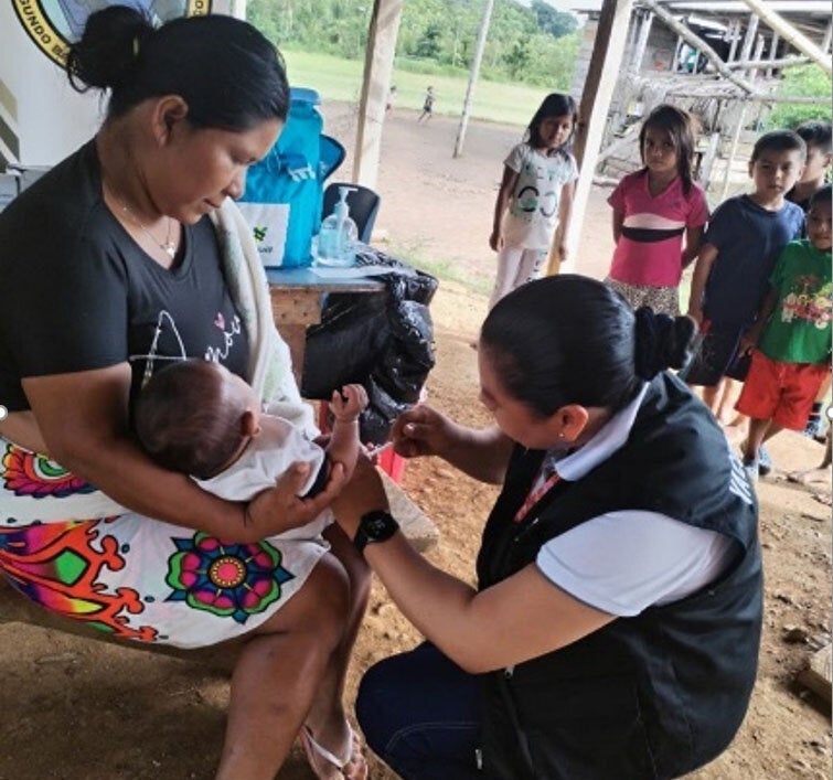 trabajadora de la salud vacuna a bebé en los brazos de su madre