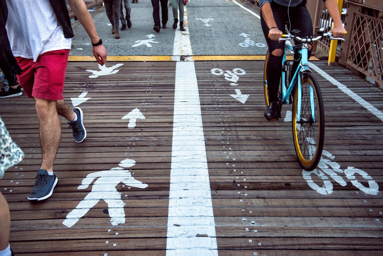 Aspecto de una vía para peatones y ciclistas, con carrilles señalizados separados para cada tipo de usuario. La foto muestra algunas piernas circulando por el carril para peationes, y una bicicleta por el de bicis
