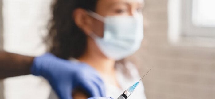 Mujer con barbijo recibiendo una inyección