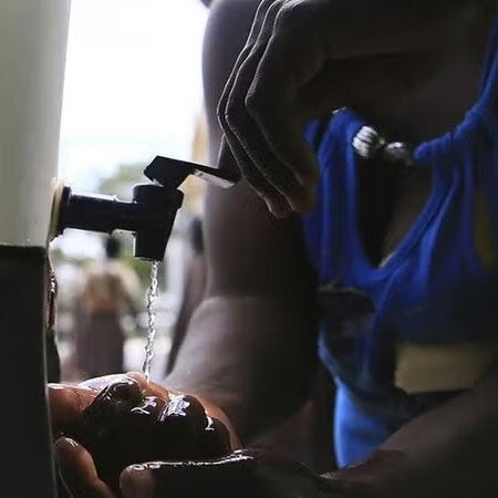 woman washing hands during cholera outbreak in Haiti