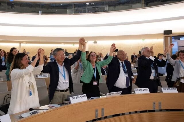 participants in the assembly hall standing cheerfully, holding hands