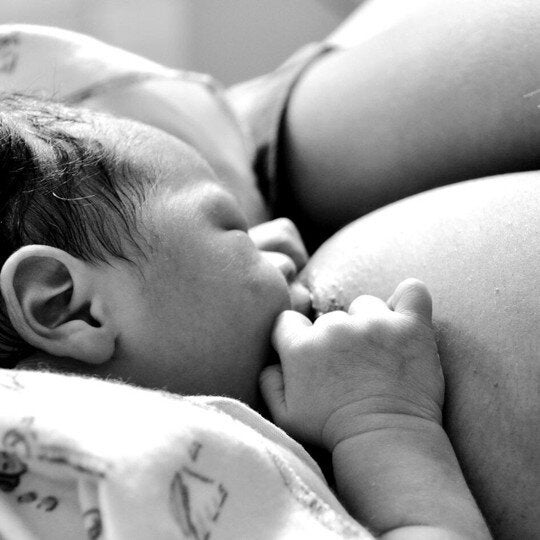 Black-and-white photo of a baby being breastfed.