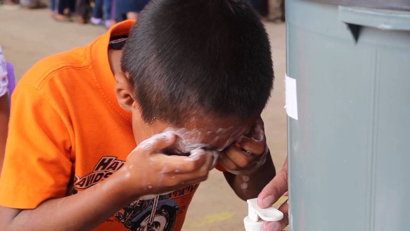 School kid washing his eyes