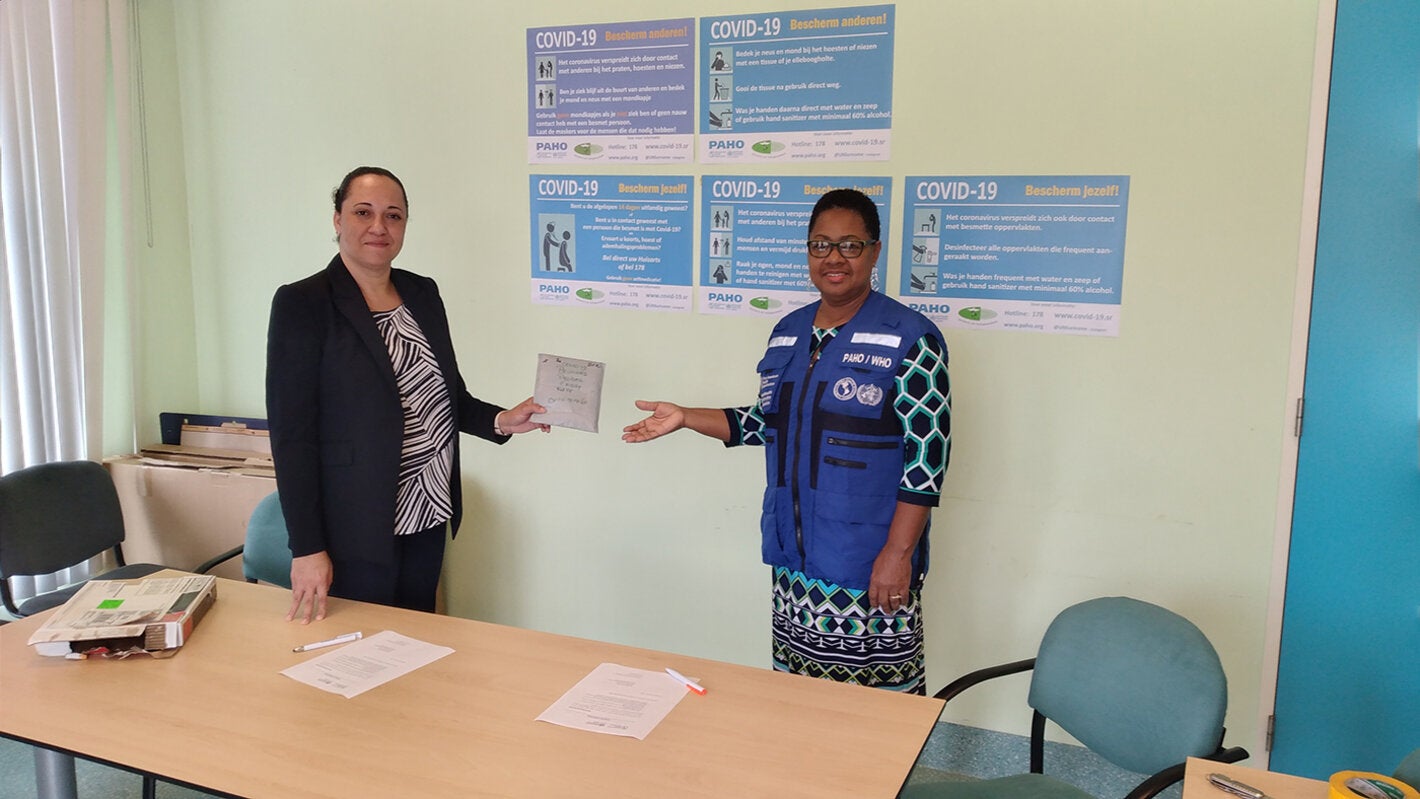 Dr. Karen Lewis-Bell hands over the COVID-19 diagnostic test kits to Dr. Cleopatra Jessurun  Director of the ministry of Public Health.