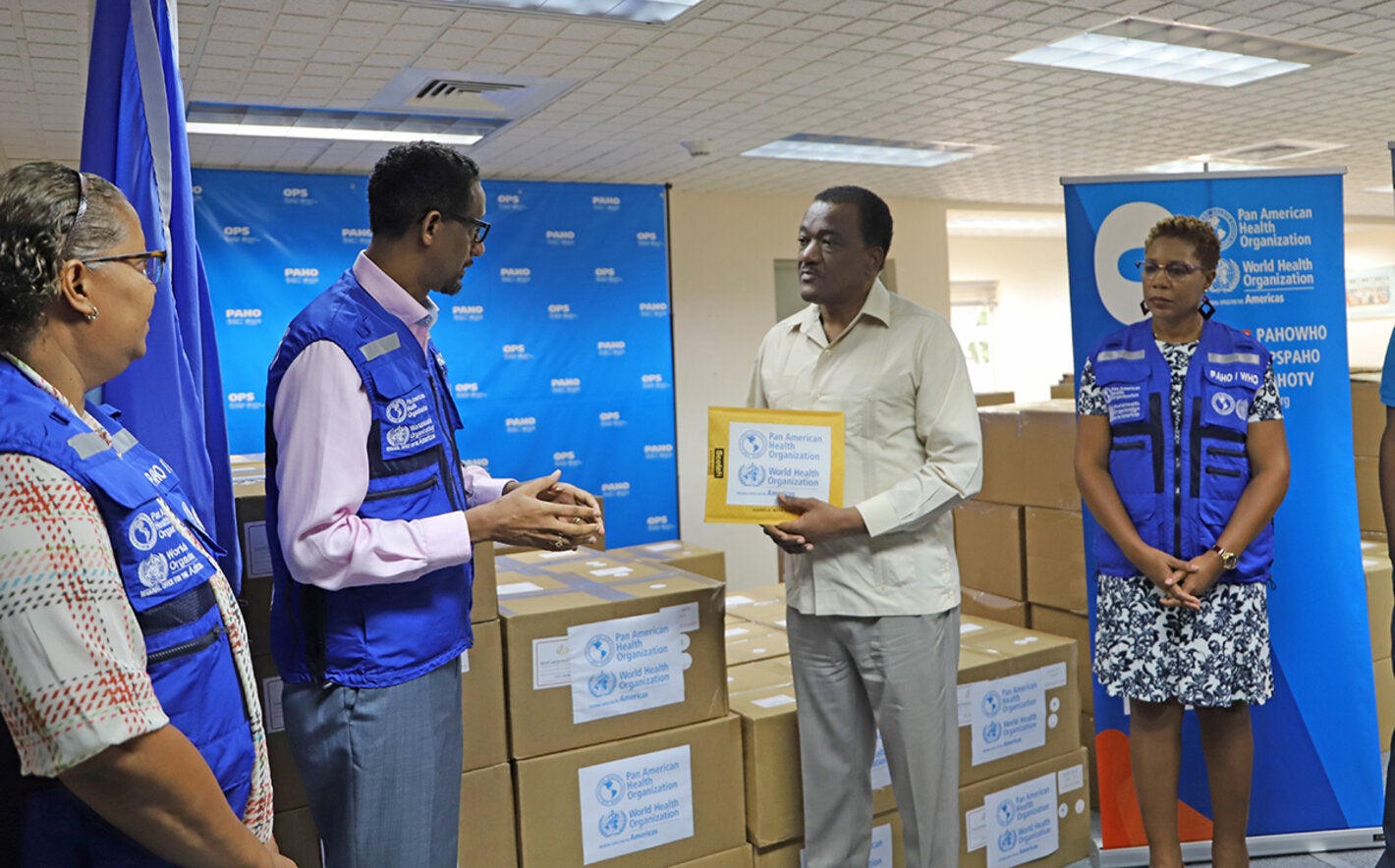 Dr Yitades Gebre – PAHO/WHO Representative to Barbados and the Eastern Caribbean Countries (2nd left) presents PPE and test kits to Lt Col Hon Jeffrey Bostic, Minister of Health and Wellness