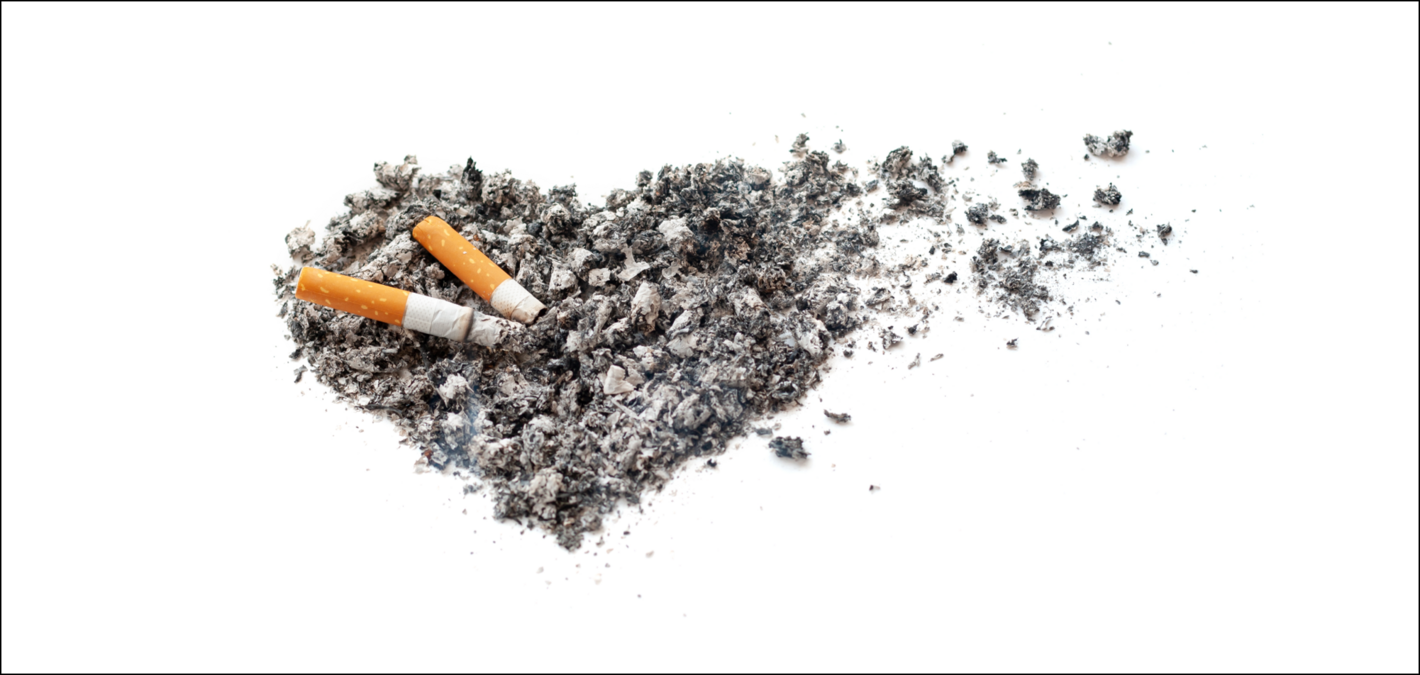 Imagen de una colilla apagándose en un conjunto de ceniza con forma de corazón. A la derecha, parte del corazón de ceniza se deshace