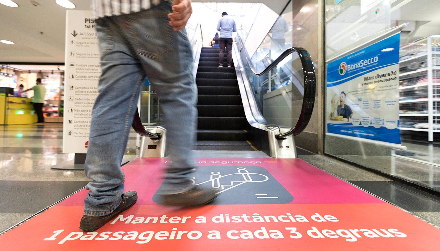 person approaching an escalator with physical distancing recommendations
