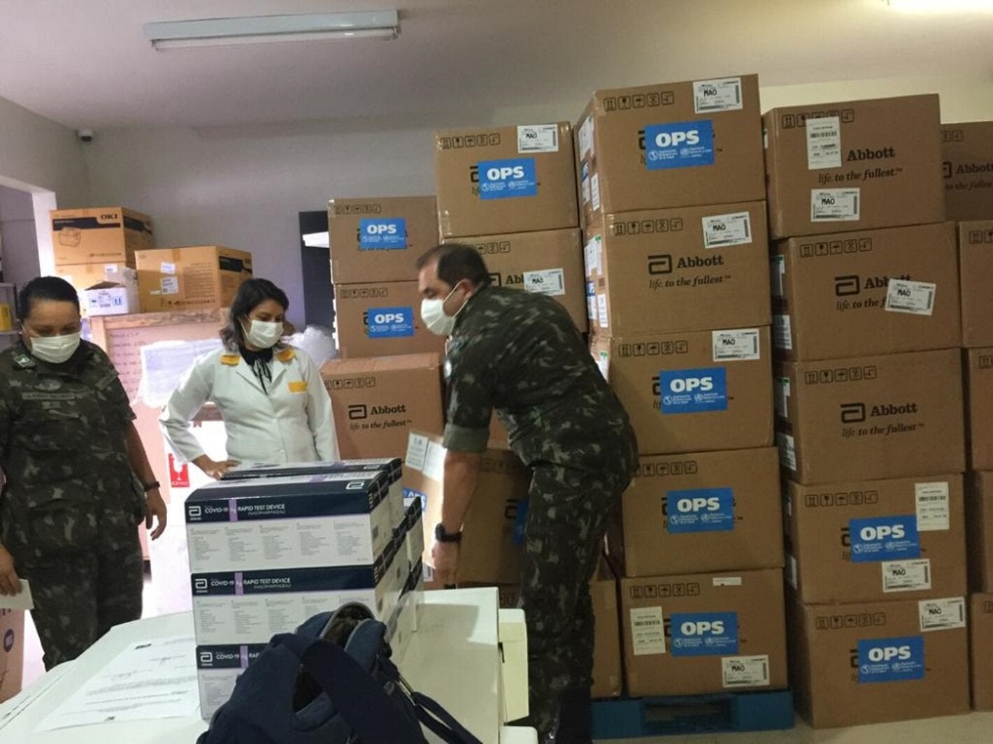 Militares da Força Tarefa da Operação Acolhida, no Brasil, carregam testes para diagnóstico de COVID-19 doados pela OPAS