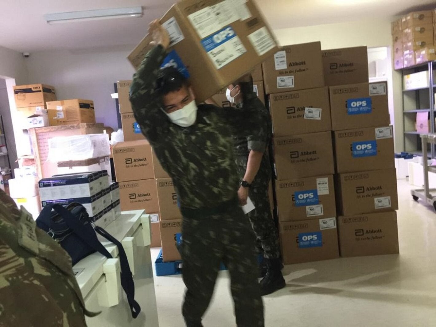 Militares da Força Tarefa da Operação Acolhida, no Brasil, carregam testes para diagnóstico de COVID-19 doados pela OPAS