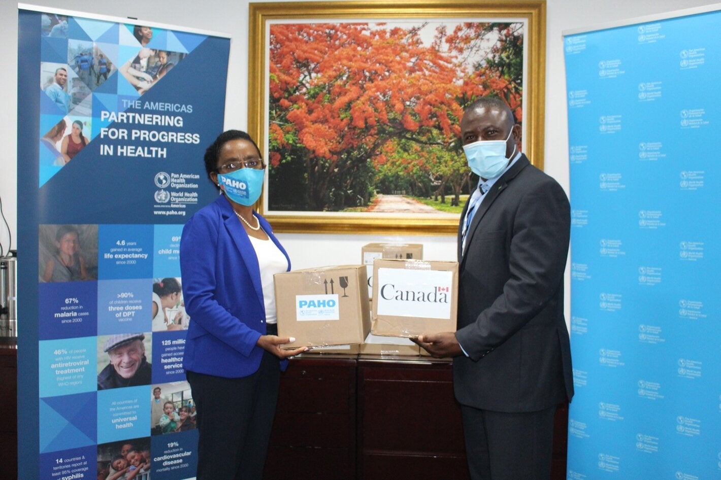 Dr Eldonna Boisson, PAHO-WHO Representative and Minister Renward Wells, Minister of Health hold donations of COVID-19 test kits 
