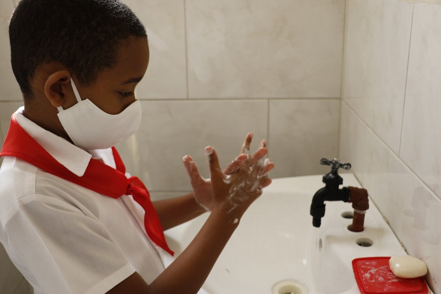 Niño se lava las manos en escuela cubana