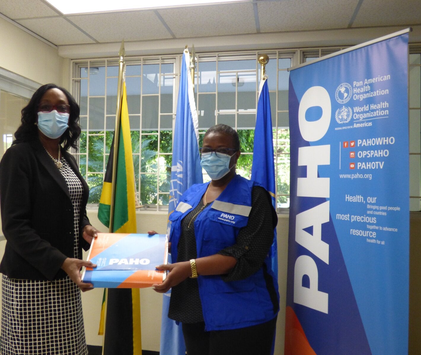 Dr. Michelle Hamilton, Director of the National Public Health Laboratory (left) receives the donation of 6000 Polymerase Chain Reaction (PCR) tests to identify Variants of Concern of COVID-19 (VoC) from Dr. Audrey Morris, Decentralized Regional Advisor, Food and Nutrition (right) at the offices of the Pan American Health Organization/ World Health Organization in Kingston.