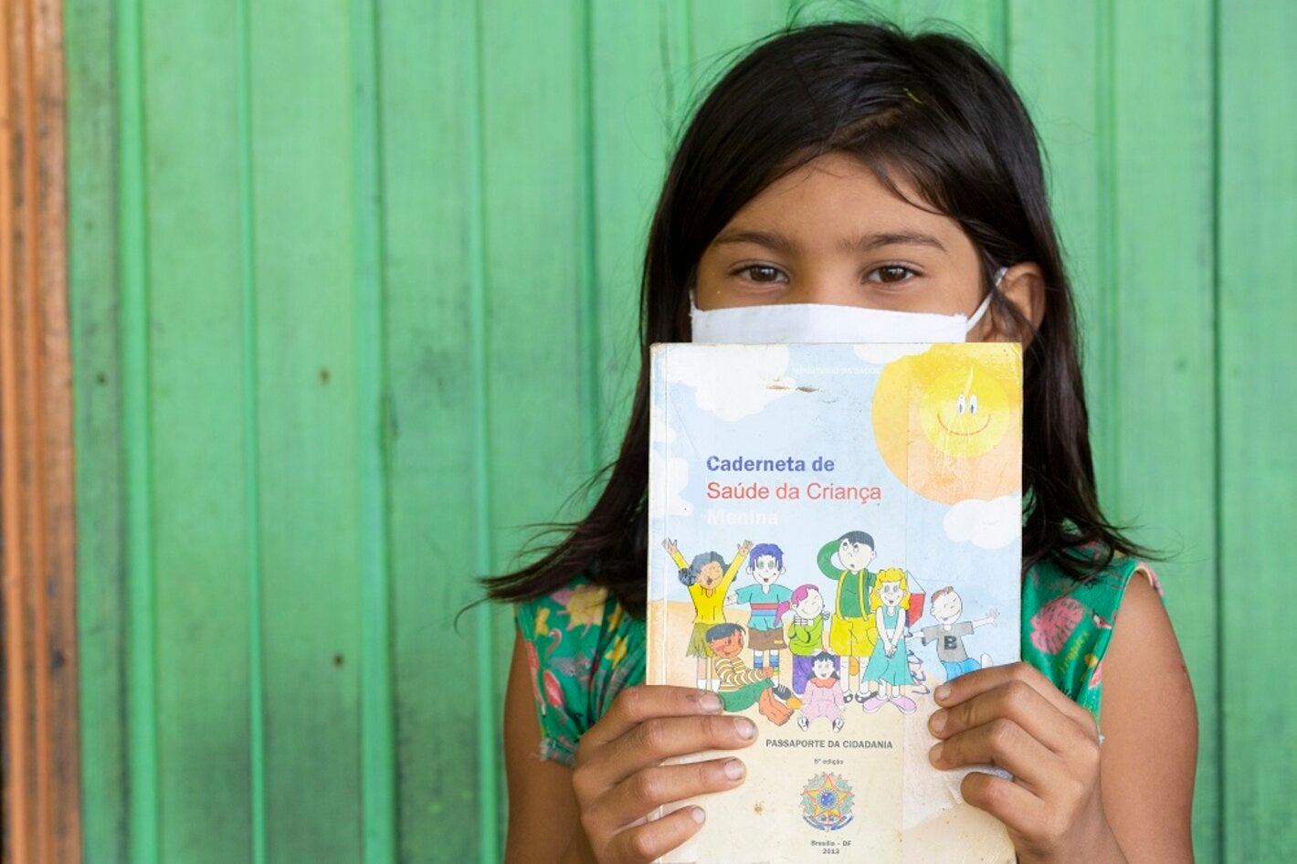 Criança segurando cartão de vacinação, no Brasil