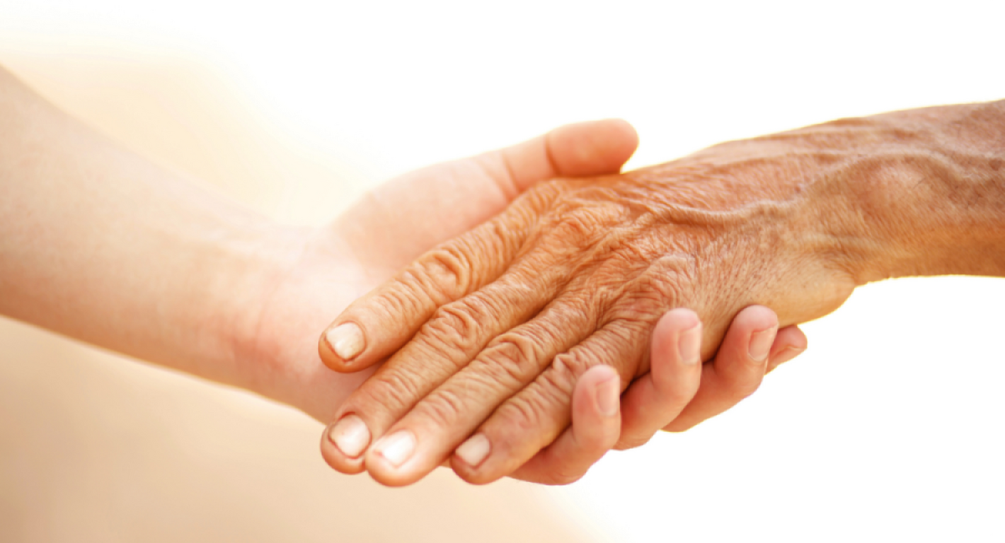 Una mano de persona joven sosteniendo la mano de una persona mayor