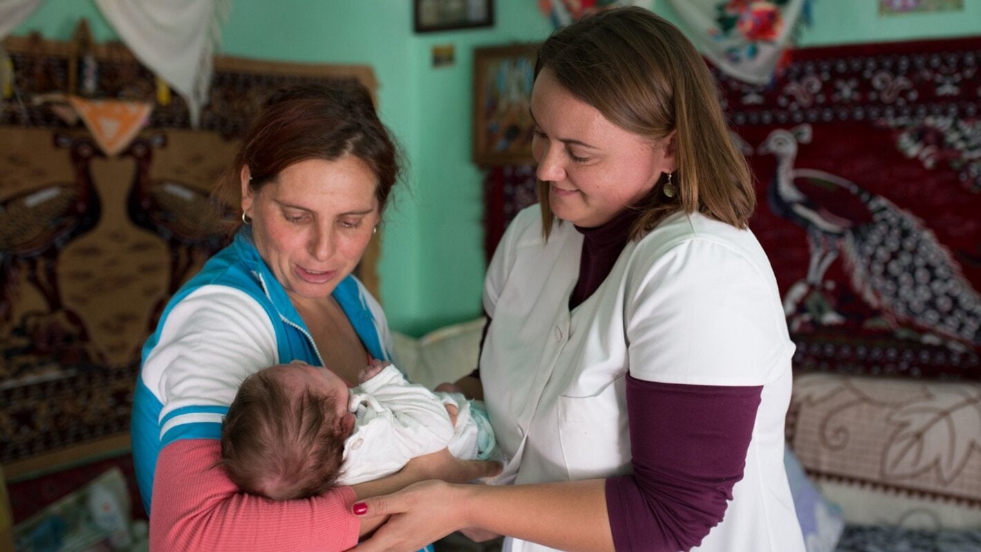 A community nurse examines a newborn baby