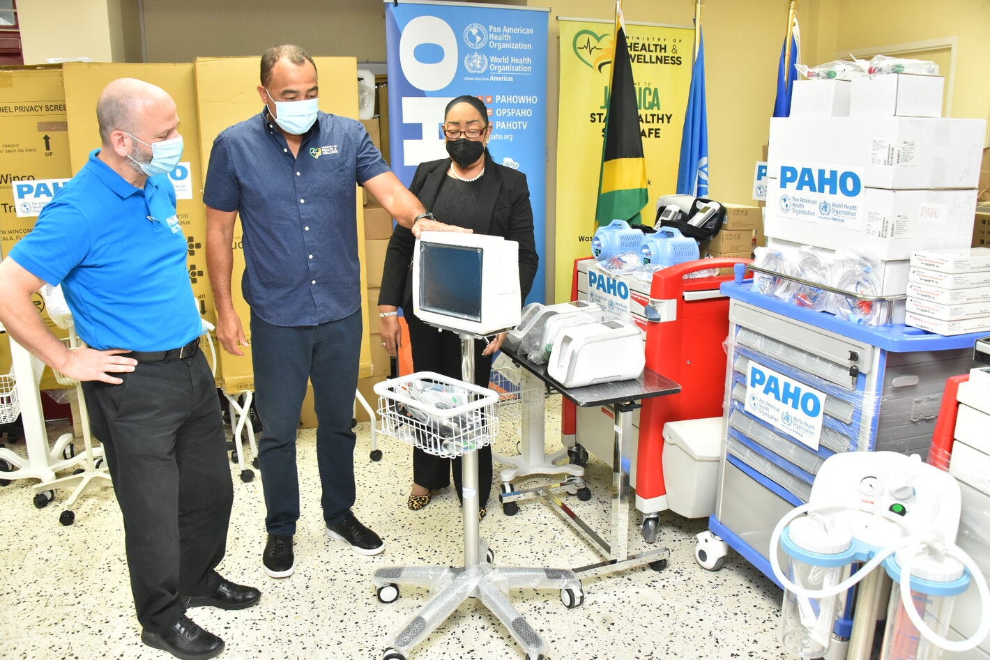 Dr. the Hon. Christopher Tufton, Jamaica's Minister of Health and Wellness (centre) discusses a patient monitor that will be used to assess the needs of a patient’s changing condition. Looking on are (L-R) Mr. Ian Stein, PAHO/WHO Representative to Jamaica, Bermuda and the Cayman Islands and Dr. Marion Bullock DuCasse, Advisor, Health Emergencies
