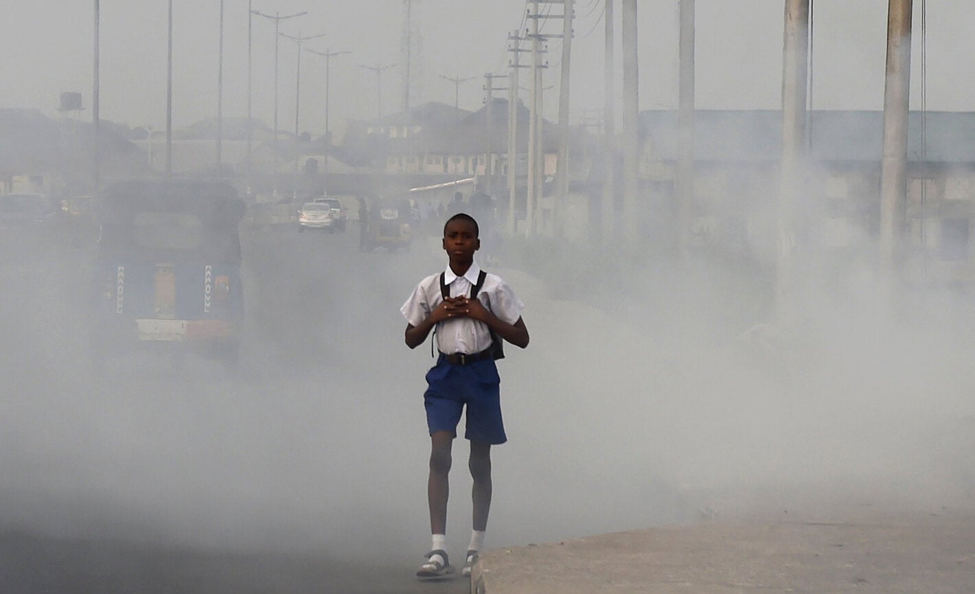 Niño caminando en ciudad con aire contaminado.