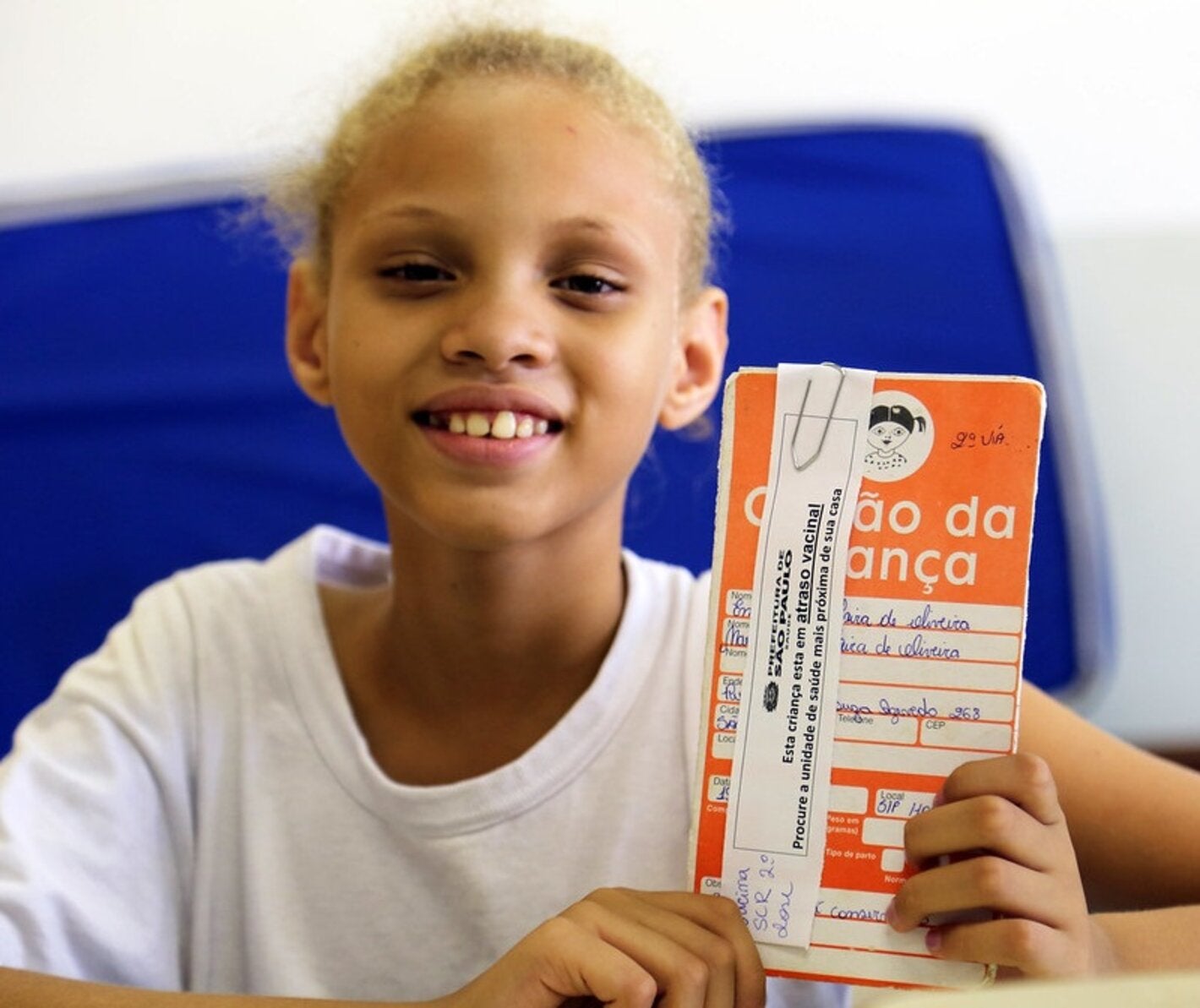 Una niña muestra su certificado de vacunación contra el VHP en Brasil