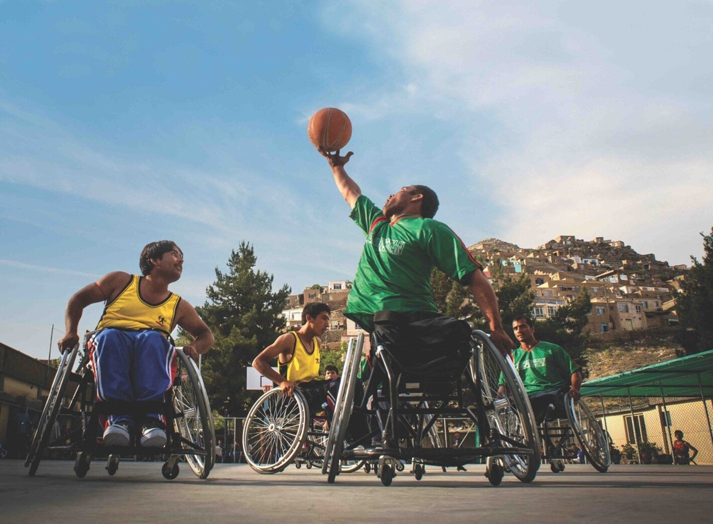 Group of young men playing basketball on wheel chairs