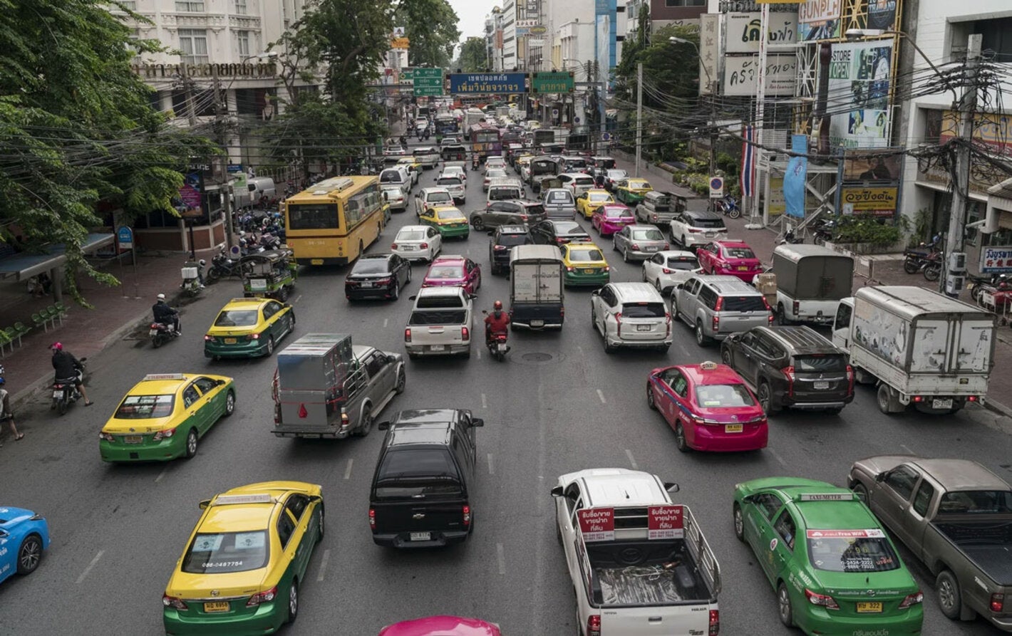 Busy urban street filled with cars and vehicles circulating in the same direction. 