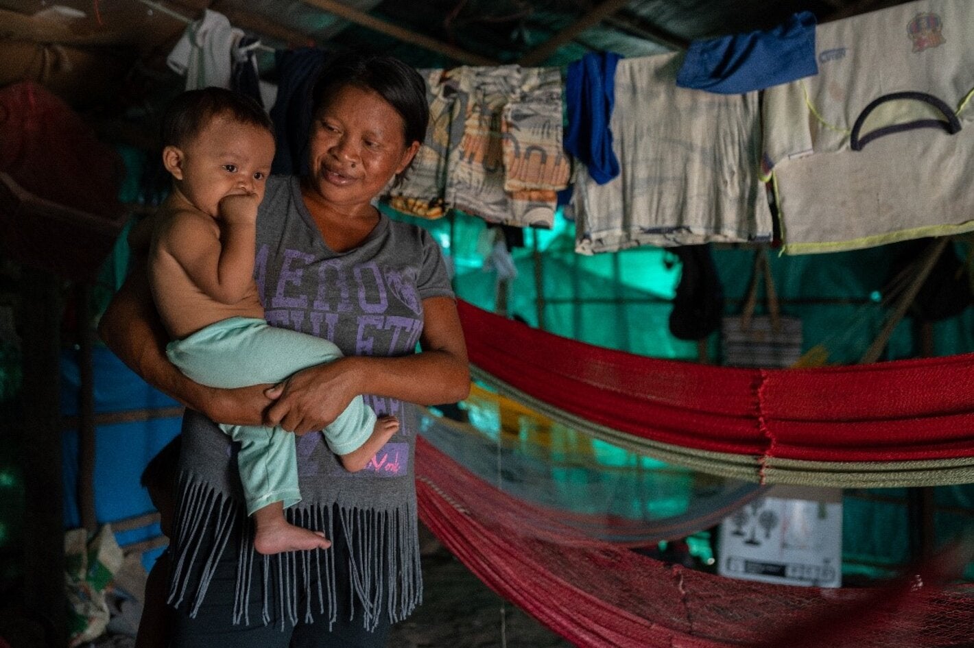 Indigenous woman carrying a toddler on her arms
