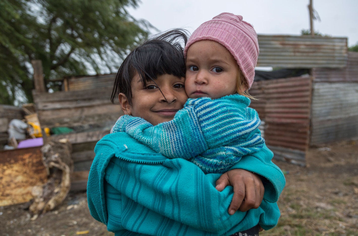 Girls with baby in her hands in impoverished area