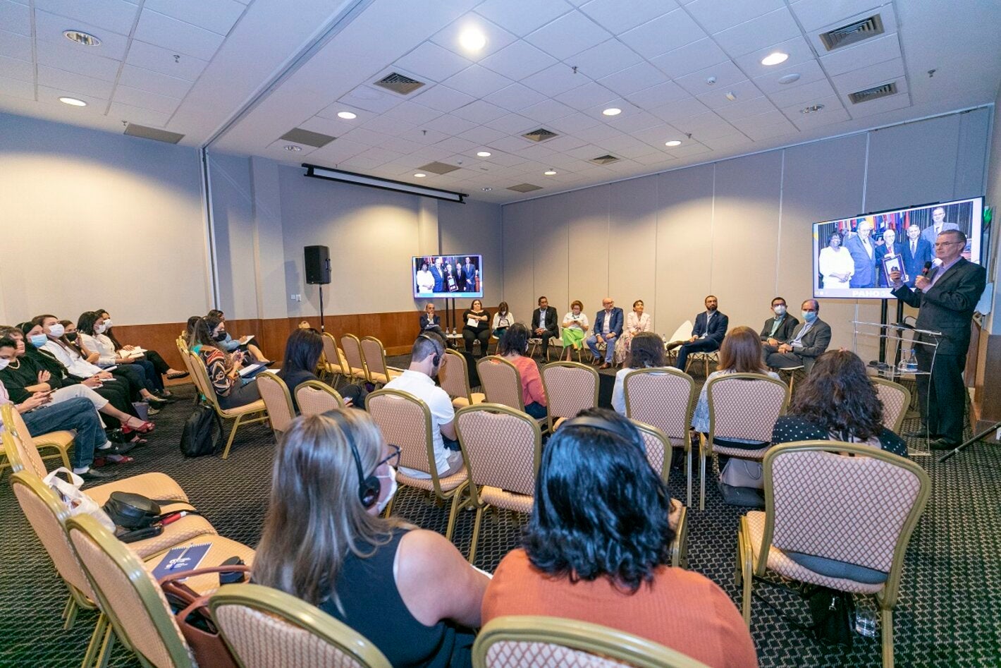 Imagem mostra pessoas em uma sala participando da Reunião Regional de Monitoramento e Reverificação da Eliminação do Sarampo no Brasil