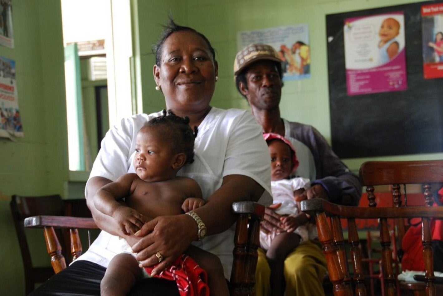Mujer sentada con bebé y, más atrás, hombre con bebé