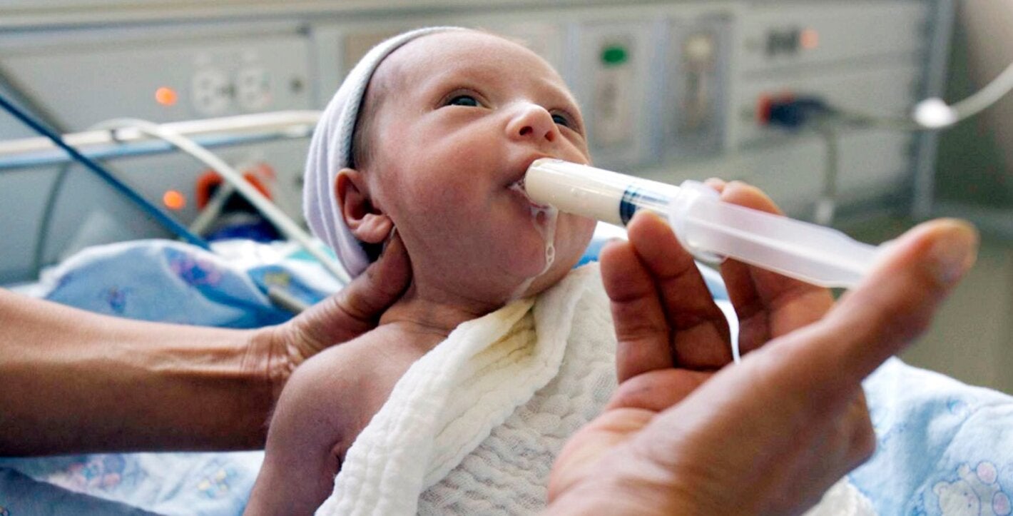 Bebé siendo alimentado de leche humana a través de una jeringa
