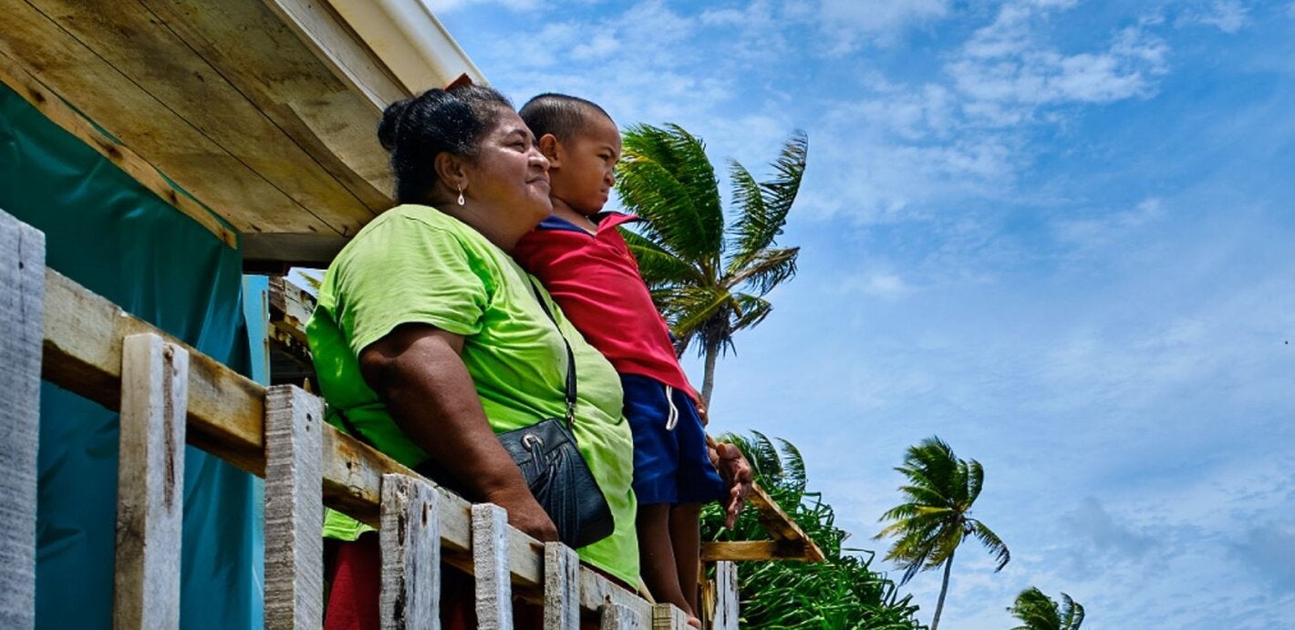 A woman and a boy looking out from a wood house
