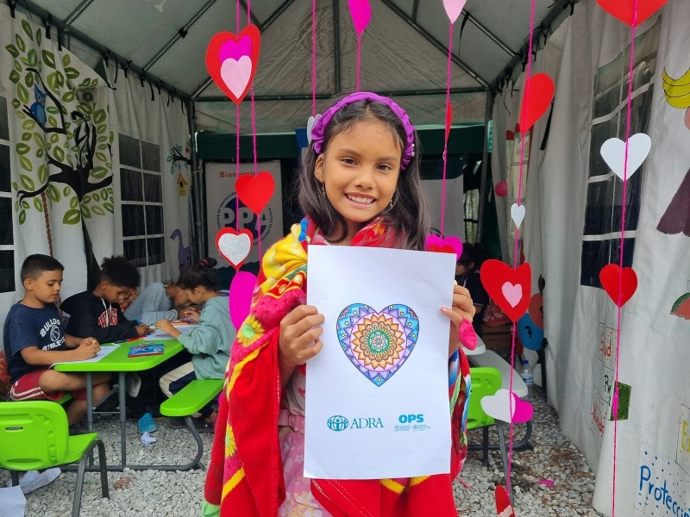 Niña migrante en Machuca, Ocotepeque, muestra su dibujo en jornada de salud mental