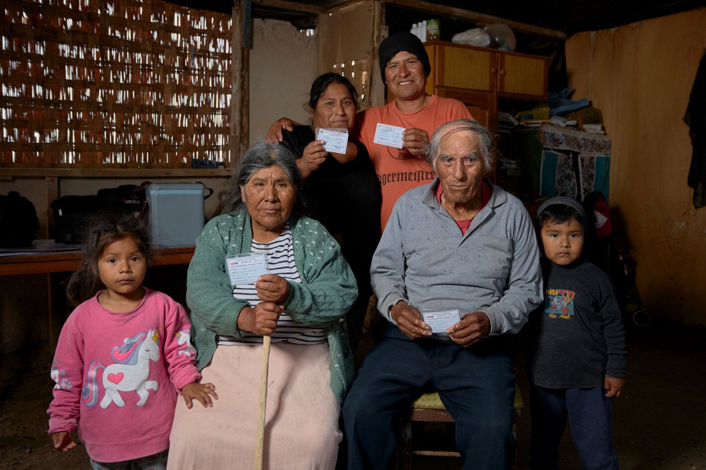 family holding up their vaccination cards at home