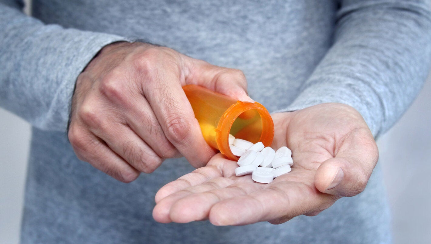Man pours pills from a jar on his open palm.