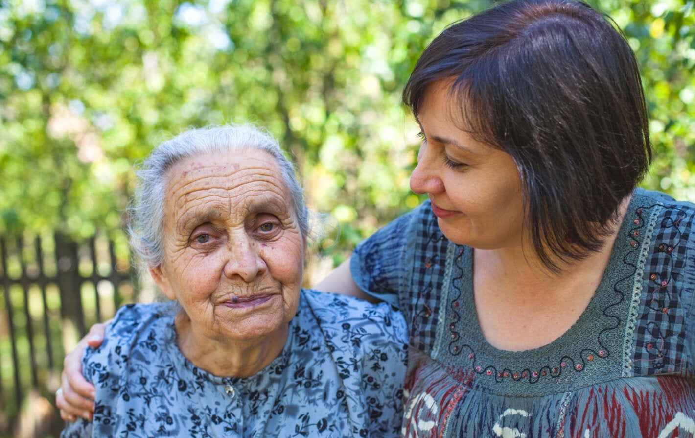 Hija abraza a madre mayor en el jardín