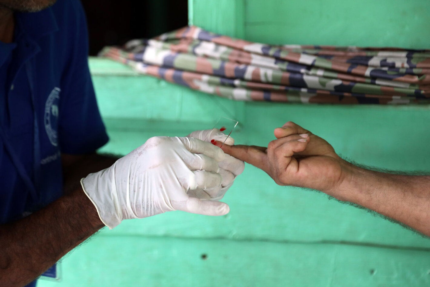 Health worker takes sample from patient to test for the presence of malaria