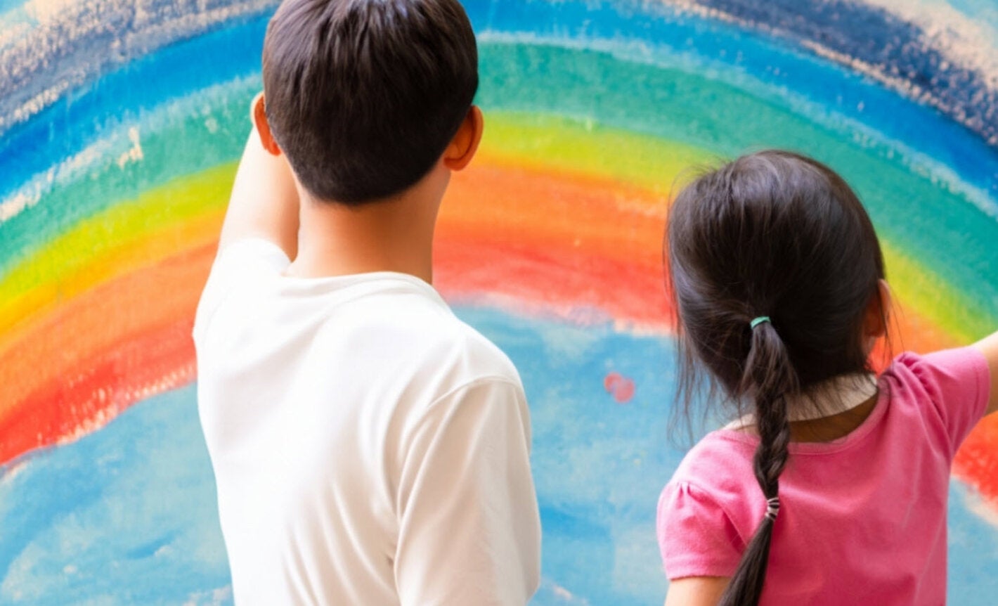 A boy and a girl looking at at painting of a rainbow